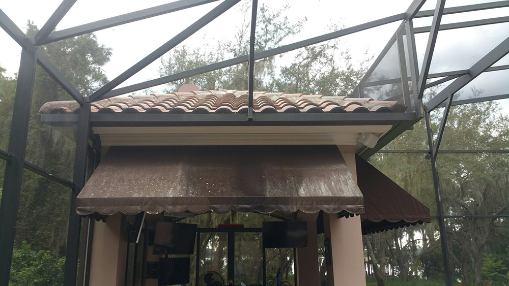 A dirty awning above an outdoor kitchen and lounge area that is desperately in need of cleaning